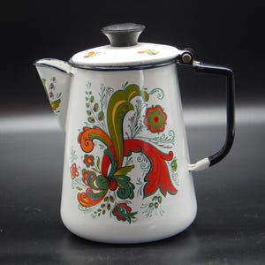 May include: White enamelware teapot with a black handle and lid. The teapot is decorated with a colorful floral design in red, green, orange, and yellow. The spout and rim are trimmed in black.