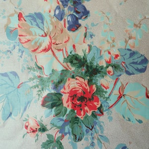 May include: A fabric featuring a floral design with large blooms and foliage. The flowers are predominantly red, pink, and peach, with blue and green leaves. The background is a pale grey with a speckled texture.