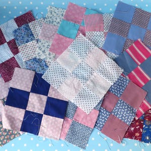 May include: A collection of patchwork quilt squares in various colors and patterns. The squares feature floral, polka dot, and striped fabrics in shades of blue, pink, and burgundy. The squares are arranged on a light blue polka dot background.