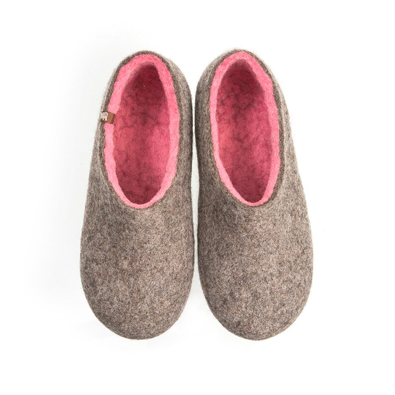 May include: A pair of gray felt slippers with pink felt lining. The slippers have a rounded toe and a flat sole.