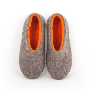 May include: A pair of gray felt slippers with orange felt lining. The slippers have a rounded toe and a flat sole.