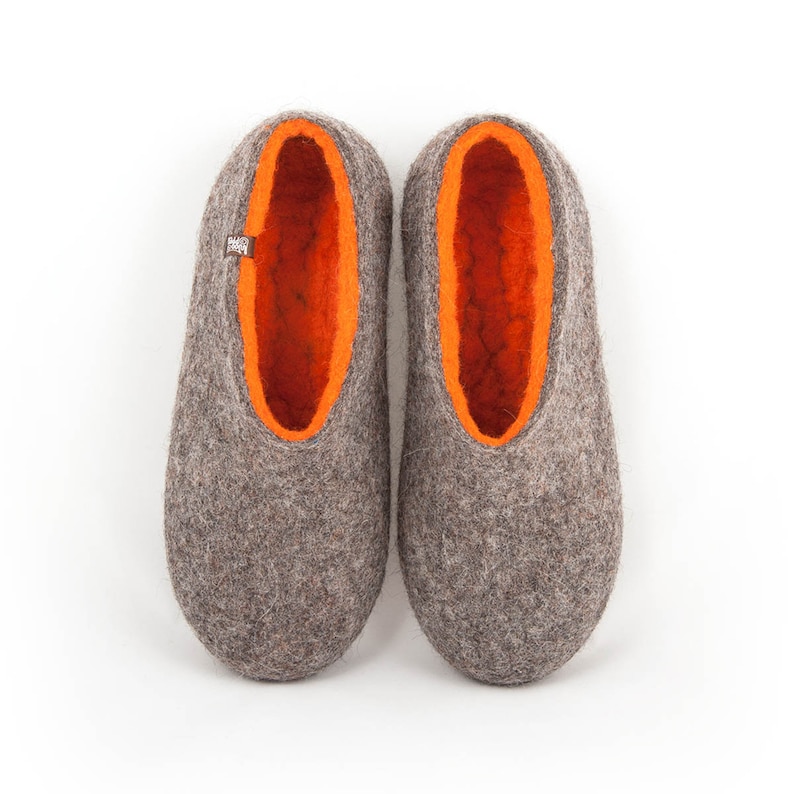 May include: A pair of gray felt slippers with orange felt lining. The slippers have a rounded toe and a flat sole.