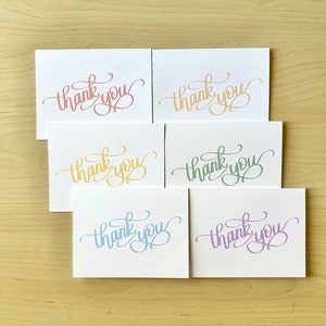 Puede incluir: Seis tarjetas de agradecimiento en blanco con caligrafía de diferentes colores. Las tarjetas están dispuestas en dos filas de tres. Los colores son rosa, melocotón, amarillo, verde, azul claro y morado.