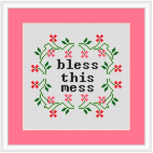 May include: Cross-stitch embroidery with a white background and a floral wreath surrounding the text "bless this mess" in black.