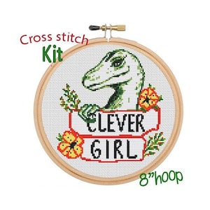 May include: Cross stitch kit featuring a green dinosaur with the text "Clever Girl" in a red and white banner. The kit includes an 8-inch hoop.