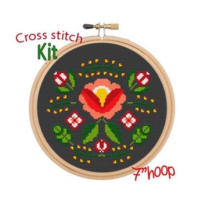 May include: Cross stitch kit featuring a floral design with a red, orange, and yellow flower surrounded by green leaves and yellow dots on a dark gray background. The kit includes a 7-inch hoop.