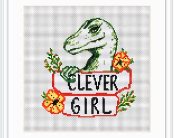 May include: Cross stitch pattern featuring a green dinosaur with a banner that reads "Clever Girl". The dinosaur is surrounded by red and yellow flowers and green leaves.