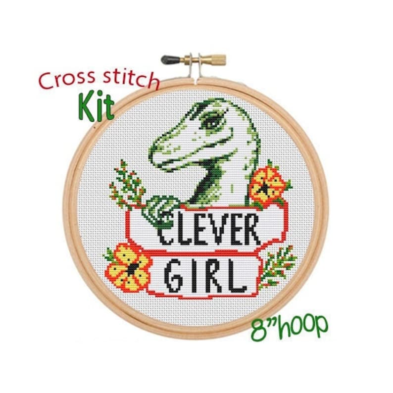 May include: Cross stitch kit featuring a green dinosaur with the text "Clever Girl" in a red and white banner. The kit includes an 8-inch hoop.