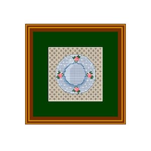Puede incluir: Un diseño de punto de cruz enmarcado que presenta un plato azul y blanco con flores rosas. El plato está rodeado de un fondo estampado beige y blanco.