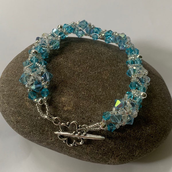 Swarovski bicones, 6 mm and 4 mm in aqua and clear with sliver plated beads in a woven bead bracelet with a sterling toggle clasp #116.