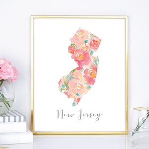 May include: A framed print featuring the state of New Jersey in a floral watercolor design. The artwork showcases a gold frame and the state outline filled with pink, peach, and teal flowers. The word "New Jersey" is written in a script font.