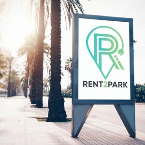 May include: A white billboard with a green and blue logo that says "RENT2PARK" and a stylized letter "R" with a keyhole inside. The billboard is on a street with palm trees.