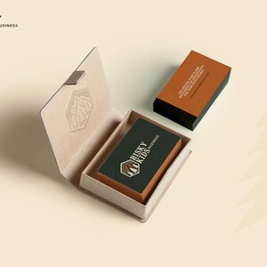 May include: A brown box with a logo for "Risky Kids Business" on the top. The box is open and a business card with the same logo is inside. The business card is on a dark green background with white text.