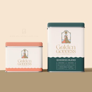 May include: Two metal coffee canisters with a pink and green lid. The canisters are labeled "Golden Goddess Coffee" and feature a graphic of a woman in a dress with long hair. The text "Goddess Blend" is printed on the green canister.