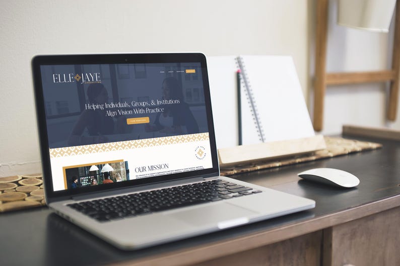 May include: A laptop computer displaying a website for a business called Elle Jaye. The website features a dark blue background with gold accents and the text "Helping Individuals, Groups, & Institutions Align Vision With Practice". The website also includes a section titled "Our Mission".