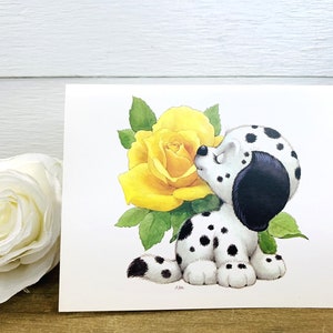 May include: A black and white dalmatian puppy with a black nose and ears is sniffing a yellow rose with green leaves. The puppy is sitting on its hind legs and has its front paws on the ground.
