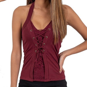 May include: A burgundy halter top with a lace overlay and a lace-up front. The top is worn by a person with long brown hair.