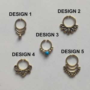 Op de afbeelding: Vijf verschillende ontwerpen van gouden neusringen. De ontwerpen omvatten een ​​eenvoudige ring met drie banden, een ring met een decoratief bloemmotief, een ring met een turquoise steen, een ring met een decoratief bloemmotief en een ring met een decoratief ontwerp met drie banden.