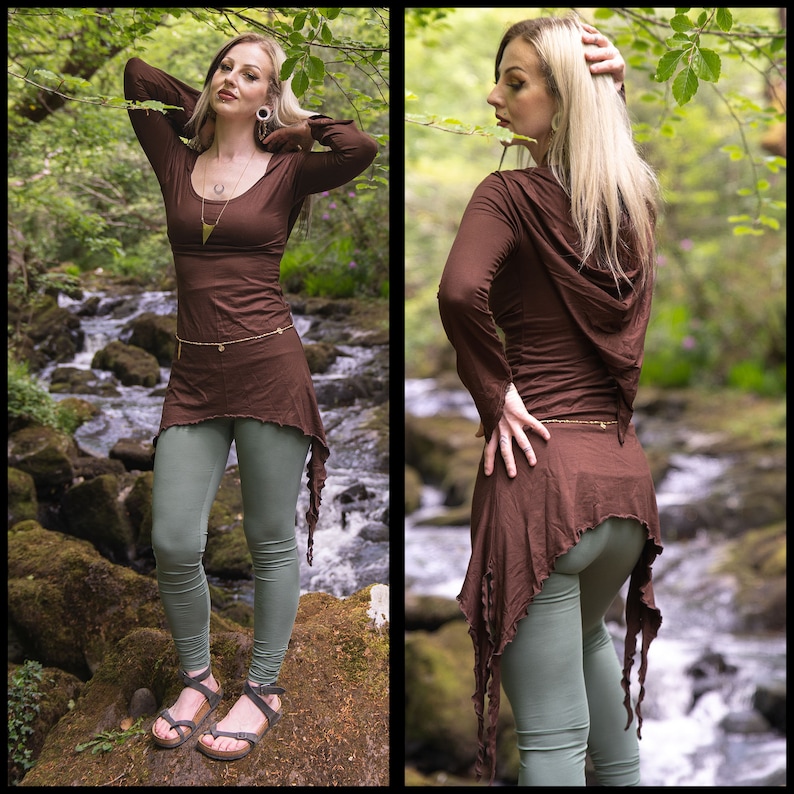 May include: A brown hooded top with long sleeves and a high neckline. The top has a flowing, asymmetrical hemline with frayed edges. The model is wearing the top with green leggings.