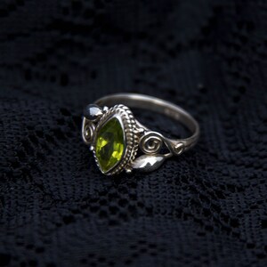 May include: A silver ring with a green gemstone set in a detailed filigree design.