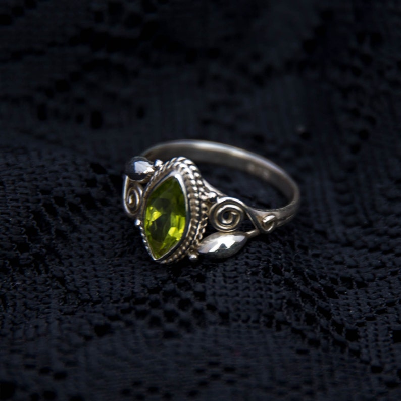 May include: A silver ring with a green gemstone set in a detailed filigree design.