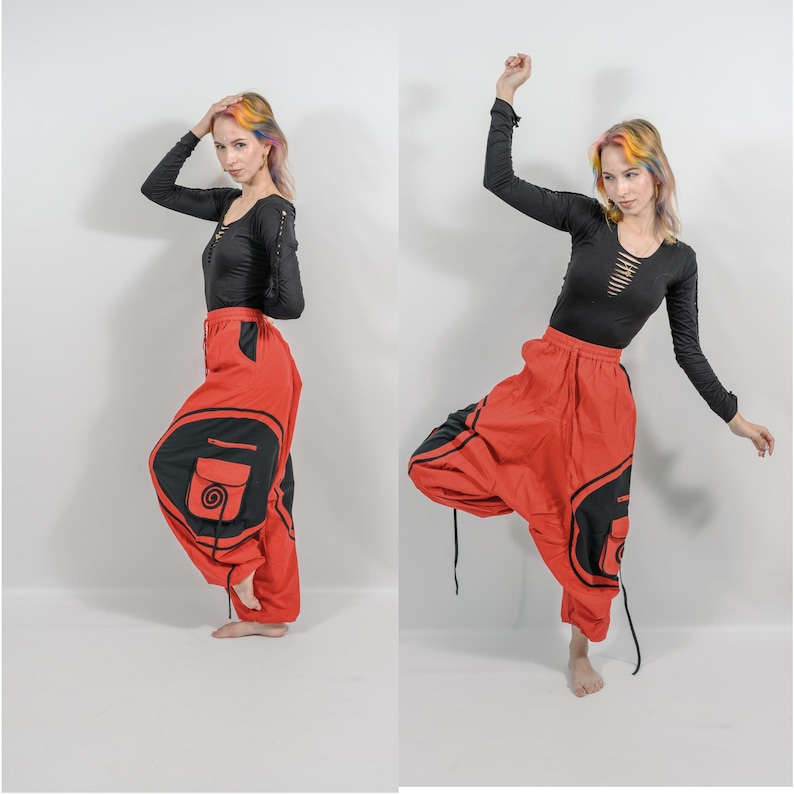 Puede incluir: Pantalones de har&eacute;n rojos y negros con un dise&ntilde;o de espiral en el bolsillo. Los pantalones tienen una cintura con cord&oacute;n y est&aacute;n hechos de una tela ligera.