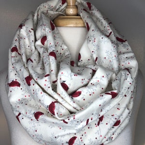 May include: White infinity scarf with a red cardinal and berry pattern.