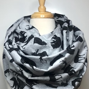 May include: A gray infinity scarf with a black print of various woodland animals, including bears, deer, and trees.