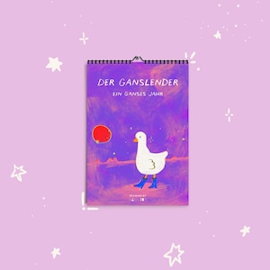 May include: A calendar with a purple background featuring a white goose wearing blue boots. The calendar has the text "DER GANSLENDER EIN GANSES JAHR" and a red sun. The calendar is hanging from a black spiral binding.