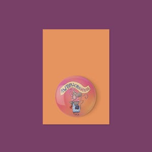 Könnte beinhalten: Ein Button mit einer Cartoon-Maus, die ein Banner mit dem Wort "Antifaschismus" hält. Der Button befindet sich vor einem orangefarbenen Hintergrund, der sich vor einem violetten Hintergrund befindet.
