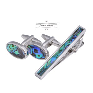 May include: A set of silver cufflinks and a tie bar featuring a blue and green abalone shell design. The word "Personalized" is printed on a white background.
