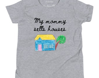 May include: Gray t-shirt with the text "My mommy sells houses" in black cursive writing. A child's drawing of a blue house with a yellow roof and a green tree is below the text.