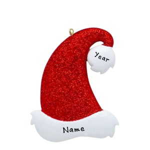May include: Red and white glitter Christmas ornament shaped like a Santa hat with the words "Name" and "Year" on it.