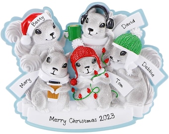 May include: A Christmas ornament featuring five white squirrels wearing winter accessories. The squirrels are holding mugs and a cup of coffee. The ornament is decorated with red and green holly and the text "Merry Christmas 2023".