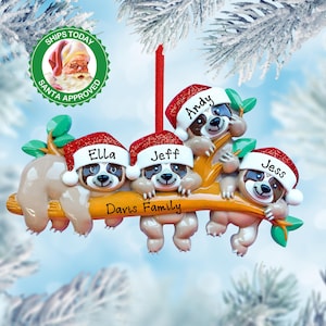 May include: A Christmas ornament featuring four sloths wearing Santa hats with personalized names: Andy, Ella, Jeff, and Jess. The sloths are hanging from a branch with the text "Davis Family" on the branch.