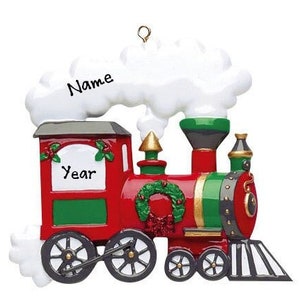 May include: A red and green Christmas ornament shaped like a train with white smoke coming from the chimney. The train has a wreath on the front and the words "Name" and "Year" on the sides.