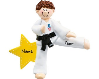 May include: A personalized Christmas ornament featuring a boy in a white karate uniform with a black belt, kicking in a star-shaped pose. The ornament is decorated with the words "Name" and "Year".