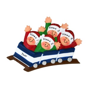 May include: A Christmas ornament featuring four figures riding a roller coaster. The figures wear Santa hats with glitter trim and are dressed in red and green. The roller coaster car is blue and white, with the word "Year" on the front.
