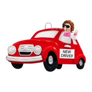 May include: Red car Christmas ornament with a person wearing sunglasses and a pink shirt driving the car. The car has a sign that says "NEW DRIVER".