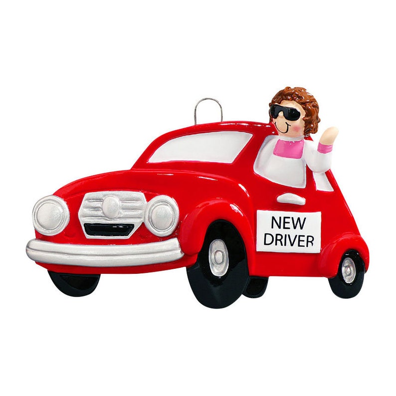 May include: Red car Christmas ornament with a person wearing sunglasses and a pink shirt driving the car. The car has a sign that says "NEW DRIVER".