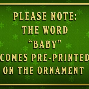K&ouml;nnte beinhalten: Ein gr&uuml;nes Schild mit goldener Umrandung und einem Schneeflockenmuster. Das Schild lautet "PLEASE NOTE: THE WORD "BABY" COMES PRE-PRINTED ON THE ORNAMENT".