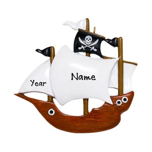 May include: A personalized wooden pirate ship Christmas ornament with a white sail, a black skull and crossbones flag, and the words "Name" and "Year" on the sail.