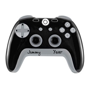 May include: A black and gray video game controller ornament with the words "Jimmy Year" printed on the bottom. The controller has buttons and directional pads in gray and white.