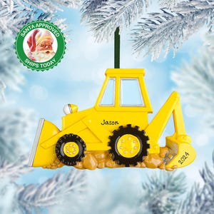 May include: Yellow toy backhoe Christmas ornament with the name Jason and the year 2024 on the side.
