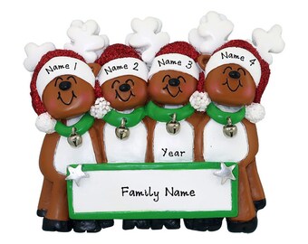 May include: A Christmas ornament featuring four reindeer with brown bodies, white antlers, and red Santa hats. Each reindeer has a green scarf with a silver bell. A white sign with a green border reads "Family Name".