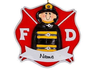 Può includere: Un ornamento rosso e argento di un vigile del fuoco con un vigile del fuoco dei cartoni animati che indossa un'uniforme nera e gialla. L'ornamento ha uno stendardo che dice "Nome".