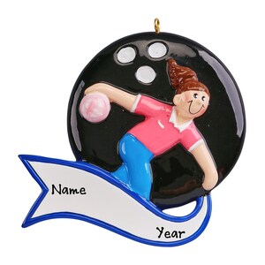 May include: A personalized Christmas ornament featuring a cartoon bowler throwing a bowling ball. The ornament is black with white pin holes and a blue and white banner with the words "Name" and "Year".