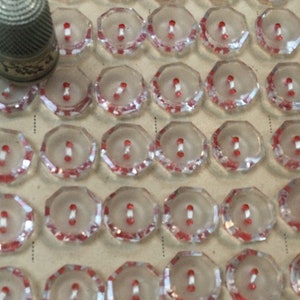 48 petits boutons anciens, en verre transparent et rouge, 1,3cm. 2 trous, forme : heptagone. 48 Antique clear glass buttons. 1920’s