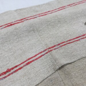 May include: A piece of off-white linen fabric with two red stripes running horizontally across the fabric.