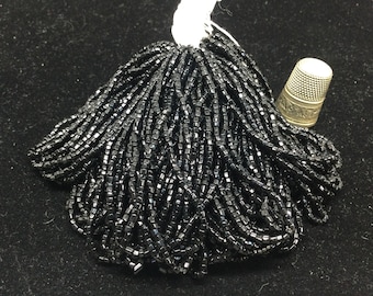 80g de perles noires, en verre, anciennes sur fil. Vintage glass seed beads on a cotton thread.